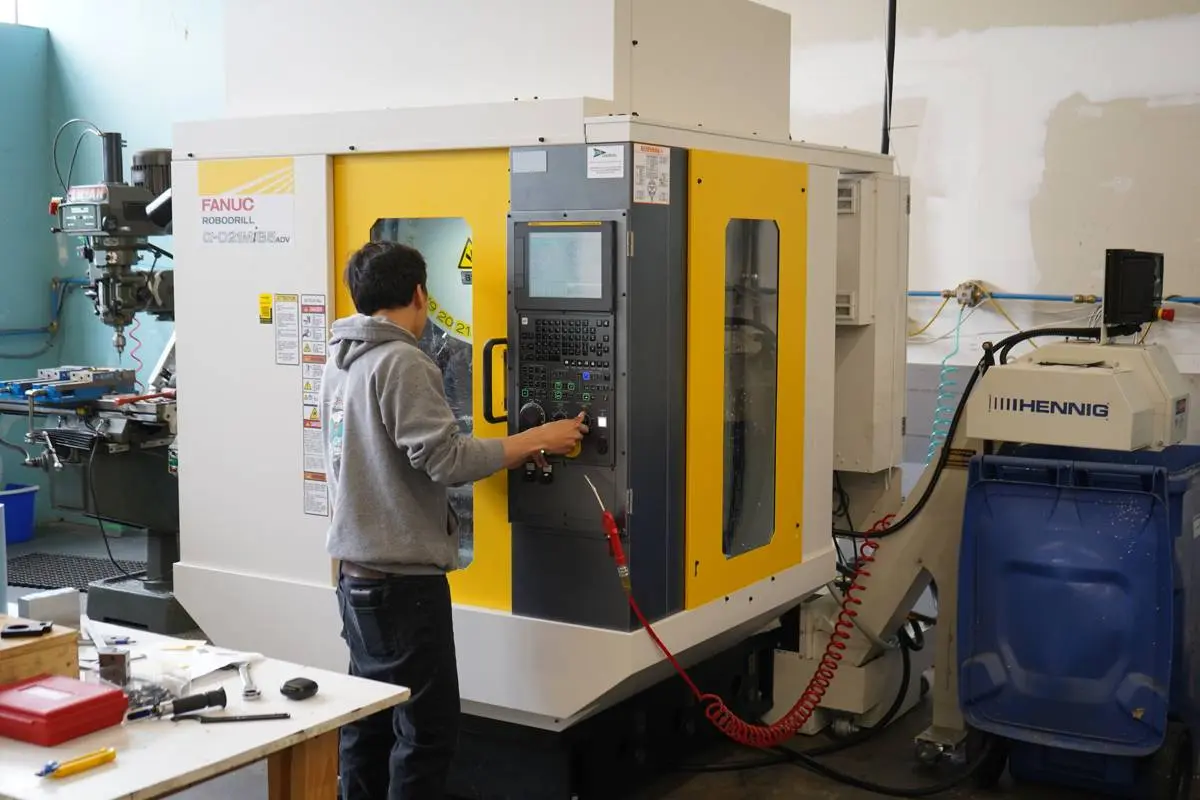 a machinist monitoring production of parts using a Fanuc Robodrill system